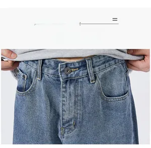 Detailed view of blue denim jeans featuring metal button closure and zip fly waist