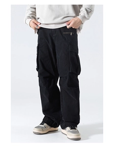 Detail view of black utility cargo pants with large side pockets and metal zipper accents
