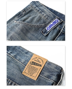 Détail de l'étiquette tissée violette et du patch en cuir sur le jean bleu délavé