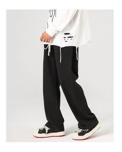 Vue latérale d'un pantalon noir ample à coupe droite avec un tombé de tissu lourd