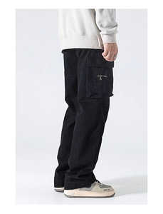 Detail view of black cargo pants with 3D flap pockets and metal zipper accents