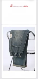 Detail of light blue straight-leg washed jeans with metal button and decorative label