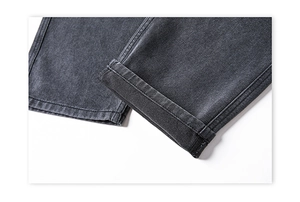 Detail of dark gray denim pants leg showing washed texture and flat stitching quality