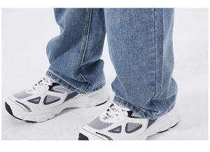 Close-up of blue washed straight-leg jeans paired with retro chunky sneakers outdoors