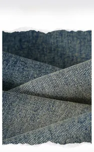 Detailed close-up of high-quality denim fabric texture with twill weave and washed blue finish