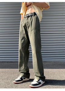 Detail view of olive green double-knee workwear pants with metal rivets and canvas texture