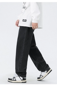 Détail d'un pantalon noir large avec écusson logo blanc et chaussures de mode chic