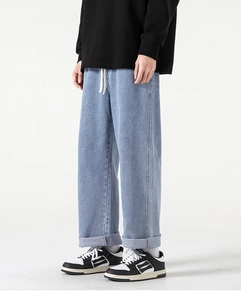 Dettaglio di jeans in denim lavato azzurro con coulisse in vita e orli con risvolto