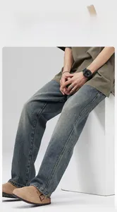 Detail view of men's loose straight-leg denim pants in vintage wash and twill texture