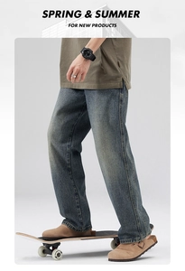 Detail of loose-fit washed blue jeans styled with a skateboard for a street fashion look