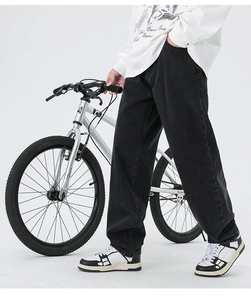 Détail d'un jean denim noir droit et large avec un style streetwear et un beau drapé