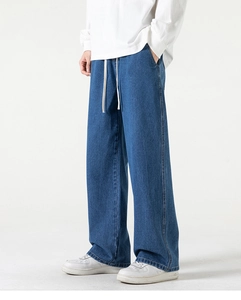 Vista laterale di jeans blu lavato da uomo a gamba larga con coulisse bianca in vita