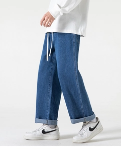 Dettaglio dei jeans blu a gamba dritta con coulisse bianca e orlo risvoltato