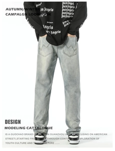 Detail of light blue straight denim pants featuring wave pattern embroidery on back pocket