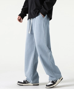 Dettaglio dei pantaloni in denim lavato azzurro con vita elastica e coulisse bianca regolabile