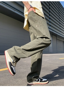 Detail view of olive green cargo pants showing functional side pockets and rivet accents