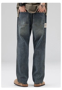 Detailed back pocket of retro washed blue straight jeans with vintage leather patch