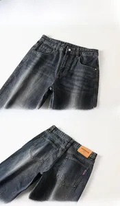 Detail show of dark blue denim jeans featuring metal button and leather brand label