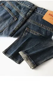 Detail of dark blue denim jeans showing leather patch and orange contrast stitching