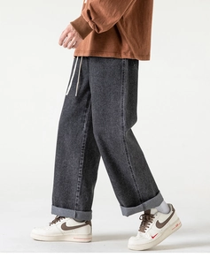 Dettaglio laterale dei jeans grigio scuro a gamba larga con coulisse e risvolto