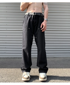 Detail of black double-knee cargo pants with metal rivets and durable canvas fabric texture