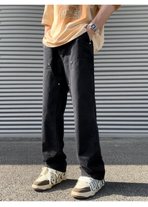 Detail of black double knee work pants with metal rivets and rugged canvas texture