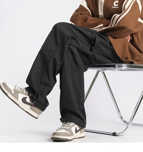 Detail of cargo pants showing adjustable elastic drawstring hem and hidden zipper side pocket