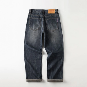 Detail of dark blue denim jeans featuring leather patch and cuffed hem from back view