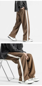 Close-up of brown corduroy trousers featuring white side stripes and a loose straight fit