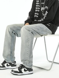 Men's light blue wash straight leg denim jeans shown in a relaxed outdoor seated pose