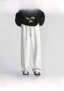 Detail of light grey straight-leg drawstring sweatpants with loose fit and textured fabric