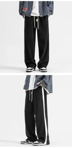 Macro shot of men's black baggy joggers with side stripe and elastic drawstring waist