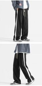 Close-up of side white stripe detail and texture on black wide-leg sports trousers