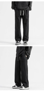 Detail of black straight-leg trousers with elastic drawstring waist and large cargo pockets
