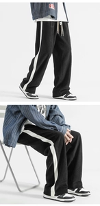 Detailed view of wide-leg sweatpants featuring contrast side stripes and drawstring waist