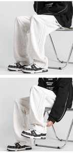 Detail of light grey wide-leg sweatpants with vertical side stitching and soft drape fabric
