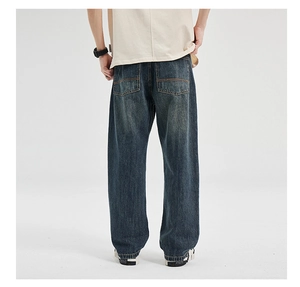 Detailed view of dark blue washed denim jeans featuring yellow contrast stitching and back pockets