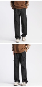 Detail of black technical cargo pants showing straight fit and adjustable drawstring hem