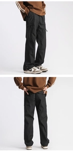 Detail view of black technical cargo pants showing side pockets and drawstring hem design