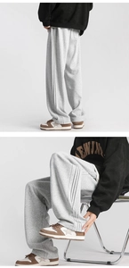 Detail view of grey drawstring sweatpants featuring classic black side stripes and relaxed fit