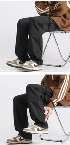 Detail view of black technical cargo pants with adjustable drawstring cuffs and woven fabric