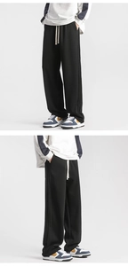 Detail of black drawstring sweatpants with side stripes and a straight leg fit