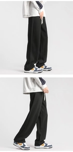 Detail of men's black straight-leg sweatpants featuring side stripes and white drawstring