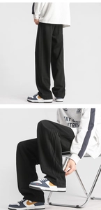 Detailed view of black wide-leg sweatpants with side stripe trim and loose fit style