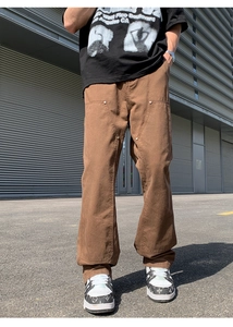 Detail of heavy brown canvas work pants featuring double knee panels and metal rivets