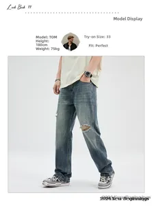 Close-up detail of blue washed denim jeans featuring distressed ripped knee design on the leg
