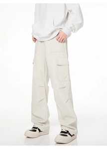 Détail du pantalon cargo blanc cassé avec grandes poches latérales et plis aux genoux