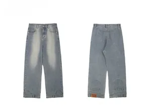 Detail of light blue straight denim jeans showing back view and orange leather brand tag