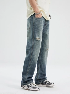 Retro washed distressed blue denim jeans with flared cut and vintage ripped hole details