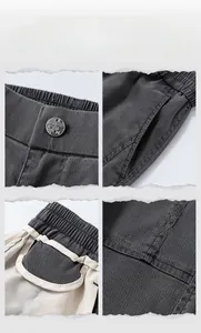 Detail of dark grey trousers showing elastic waistband, metal button, and twill fabric texture